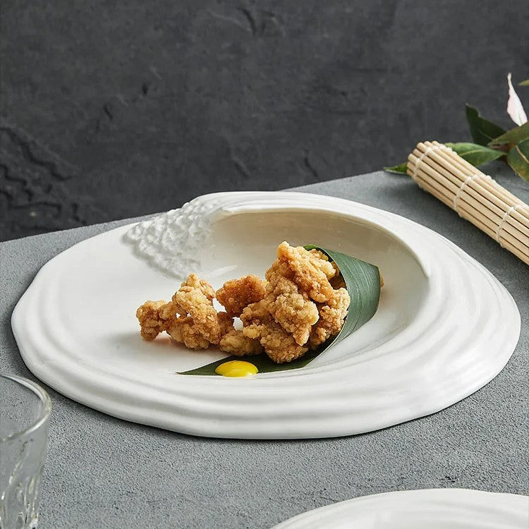 White ceramic plate with an organic textured design, featuring a unique raised edge, ideal for artistic food presentation in gourmet dining settings