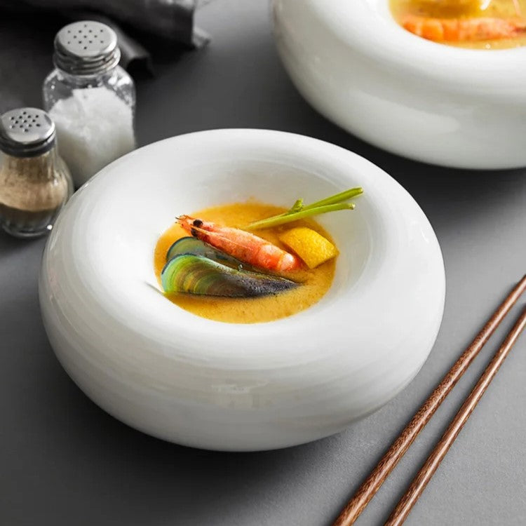 White porcelain bowl with a sculptural donut shape, designed for elegant soup and gourmet dish presentations in modern fine dining settings