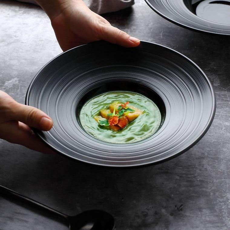 Black ceramic plate with a wide, ridged design, ideal for contemporary fine dining and elegant soup or appetizer presentations.